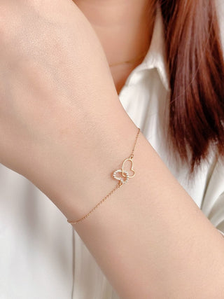 Pulsera de diamantes entrelazados con dos corazones en oro de 14 k